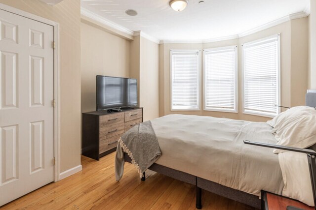 bedroom with light wood finished floors, ornamental molding, and baseboards