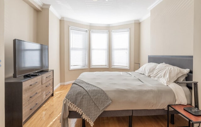 bedroom with light wood-style floors, crown molding, and baseboards