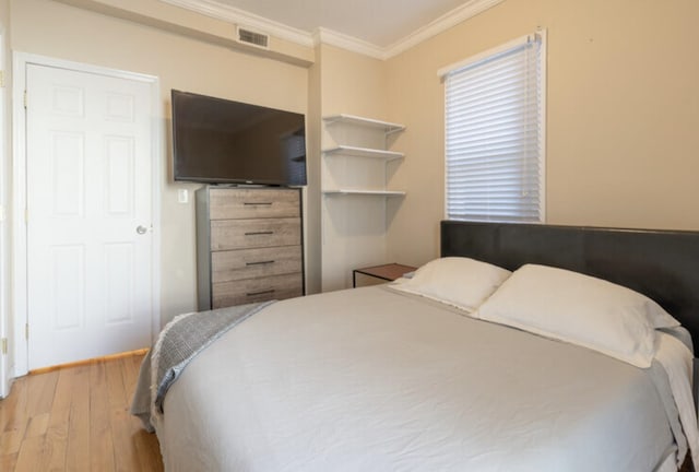 bedroom featuring ornamental molding, visible vents, and wood finished floors