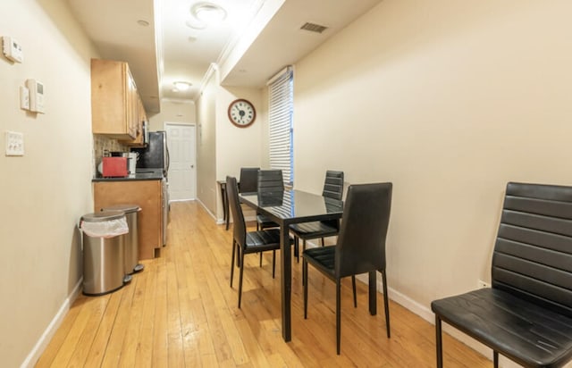 dining room with light wood-style flooring, visible vents, and baseboards