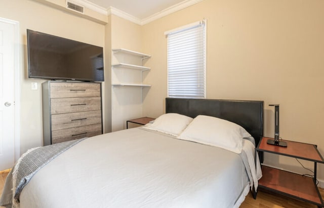 bedroom featuring visible vents, crown molding, and wood finished floors