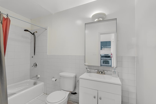 full bathroom with vanity, toilet, tiled shower / bath, and tile walls