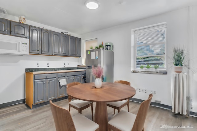 kitchen with gray cabinetry, stainless steel fridge, and light hardwood / wood-style flooring