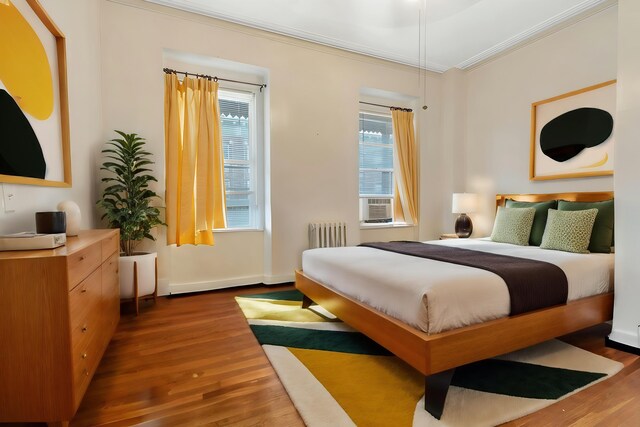 bedroom featuring ornamental molding, radiator heating unit, and dark hardwood / wood-style floors