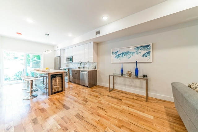 kitchen with white cabinets, appliances with stainless steel finishes, light hardwood / wood-style floors, and a center island