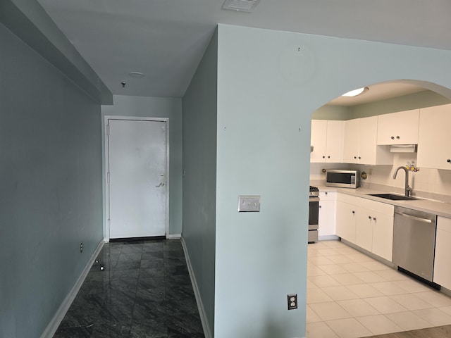 54 Polk St, Newark, NJ 07105 - kitchen with stainless steel appliances, arched walkways, white cabinetry, light countertops, and backsplash