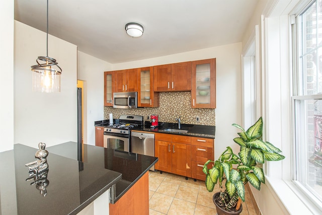 kitchen featuring appliances with stainless steel finishes, sink, decorative backsplash, hanging light fixtures, and light tile patterned floors