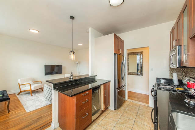 kitchen with hanging light fixtures, appliances with stainless steel finishes, kitchen peninsula, beverage cooler, and backsplash