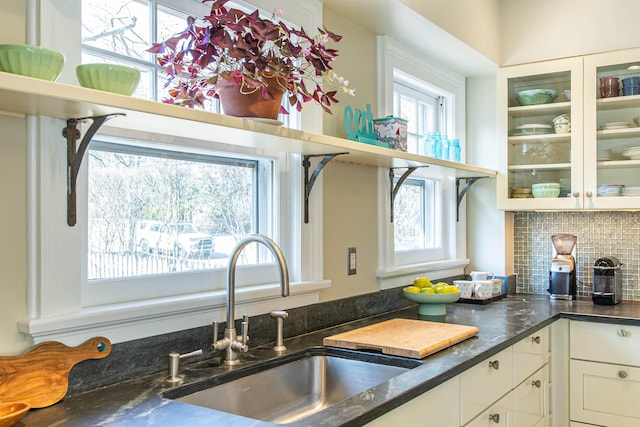 kitchen with a sink, plenty of natural light, backsplash, and white cabinetry