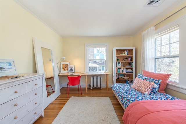 bedroom with visible vents, radiator, wood finished floors, and crown molding