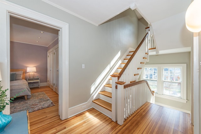 stairs featuring hardwood / wood-style floors, crown molding, and baseboards