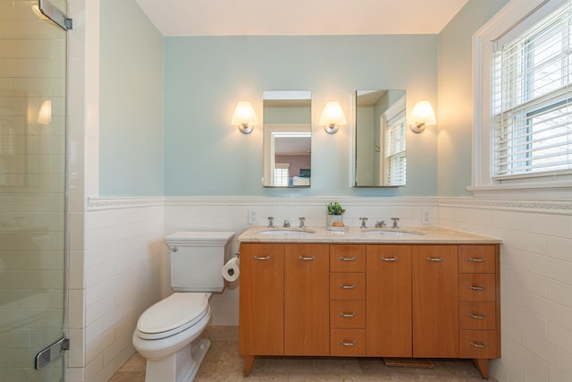 bathroom featuring tile walls, wainscoting, and a sink