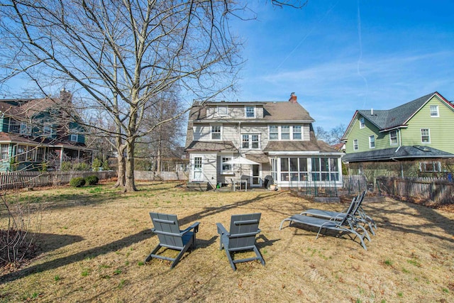 rear view of property featuring fence, roof with shingles, a sunroom, a chimney, and entry steps