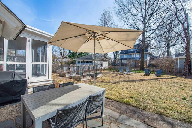 view of patio featuring outdoor dining space, a grill, fence, and a sunroom