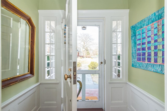 doorway to outside featuring a decorative wall and a wainscoted wall