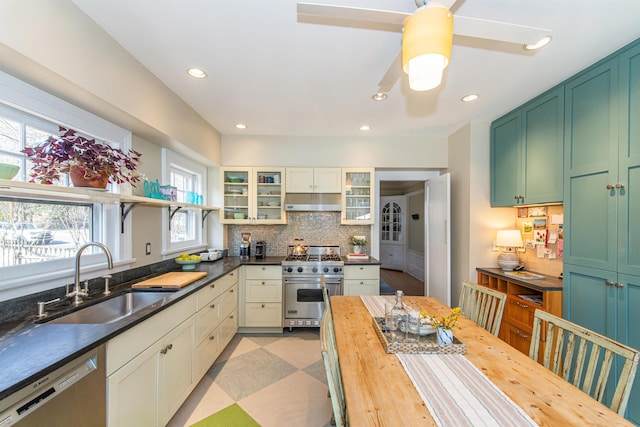 kitchen with a sink, stainless steel appliances, under cabinet range hood, backsplash, and butcher block counters