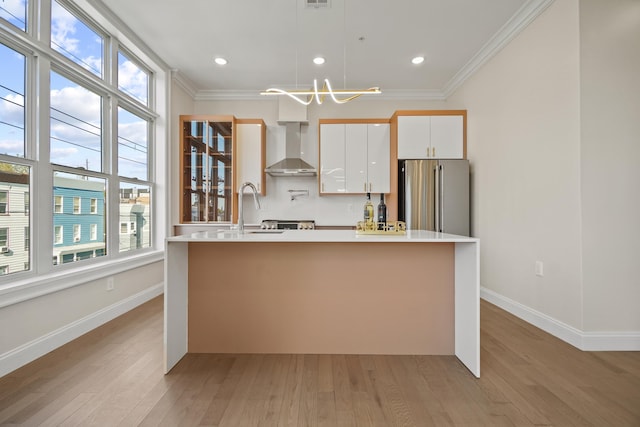 kitchen featuring white cabinetry, wall chimney exhaust hood, a center island with sink, and high end refrigerator