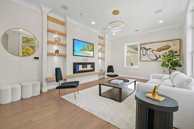 living room featuring built in shelves, a fireplace, ornamental molding, and light hardwood / wood-style floors