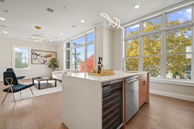 kitchen featuring pendant lighting, a center island with sink, ornamental molding, and wine cooler