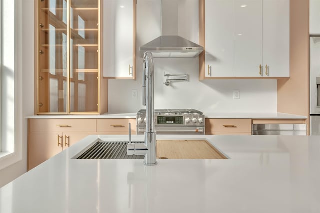 kitchen with stainless steel range oven, white cabinets, and wall chimney exhaust hood