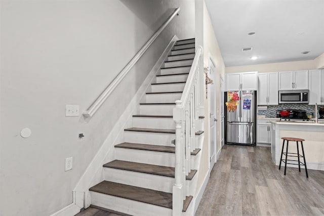 stairway featuring recessed lighting, visible vents, baseboards, and wood finished floors