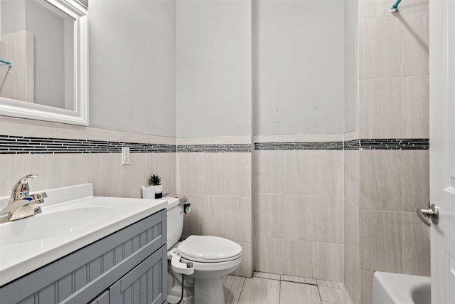 bathroom with toilet, tile walls, and vanity