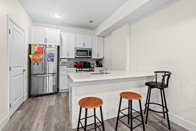 kitchen with backsplash, a breakfast bar area, a peninsula, stainless steel appliances, and a sink