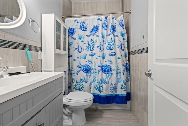 full bath with vanity, shower / bath combination with curtain, wainscoting, tile walls, and toilet