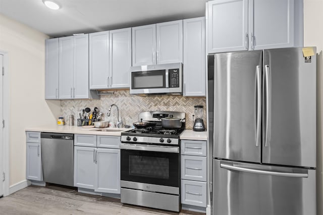 kitchen with a sink, stainless steel appliances, decorative backsplash, and light countertops