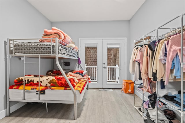 bedroom featuring wood finished floors, access to outside, french doors, and baseboards