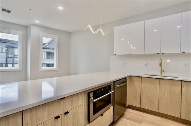 443 Bergen Ave Unit 3, Jersey City, NJ 07304 - kitchen with appliances with stainless steel finishes, light wood-type flooring, decorative light fixtures, modern cabinets, and white cabinetry