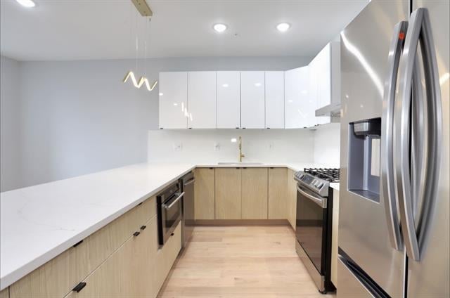 443 Bergen Ave Unit 3, Jersey City, NJ 07304 - kitchen with appliances with stainless steel finishes, light brown cabinets, modern cabinets, light wood-type flooring, and pendant lighting
