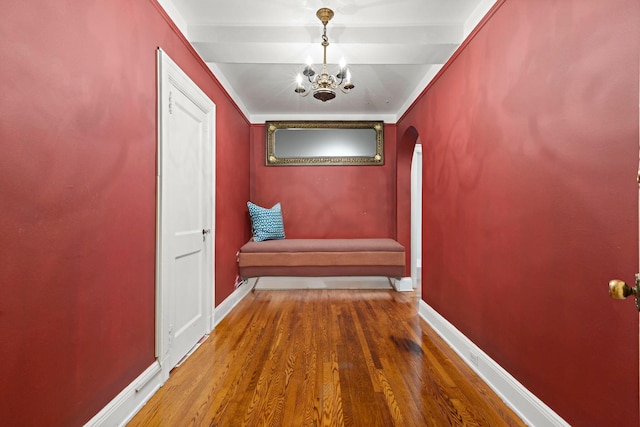 hallway featuring a notable chandelier, crown molding, and hardwood / wood-style flooring