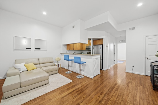 living room featuring recessed lighting, baseboards, visible vents, and light wood finished floors