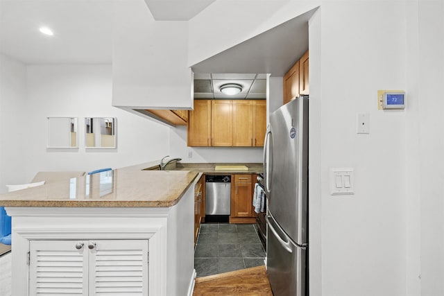 kitchen with stainless steel appliances, brown cabinets, and a peninsula