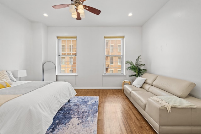 bedroom featuring multiple windows, wood finished floors, recessed lighting, and baseboards