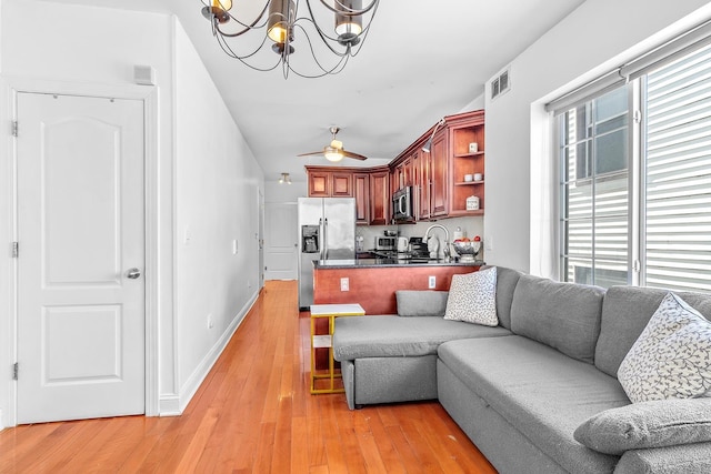 living area with an inviting chandelier, light wood-style flooring, baseboards, and visible vents