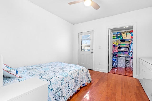 bedroom featuring a spacious closet, baseboards, ceiling fan, hardwood / wood-style floors, and a closet