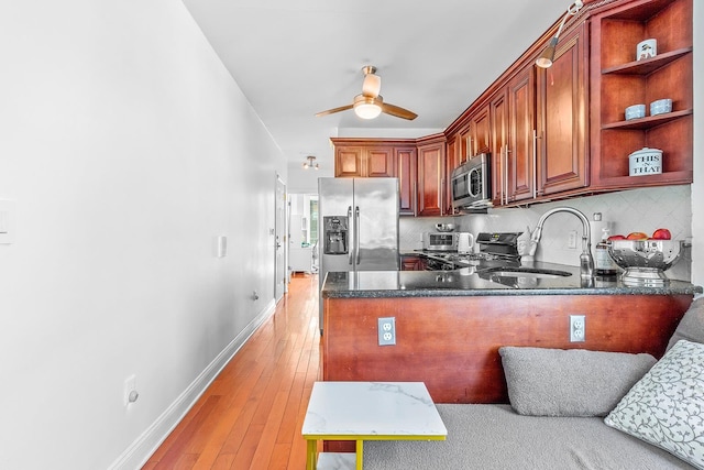 kitchen featuring backsplash, light wood-style flooring, stainless steel appliances, a ceiling fan, and a sink