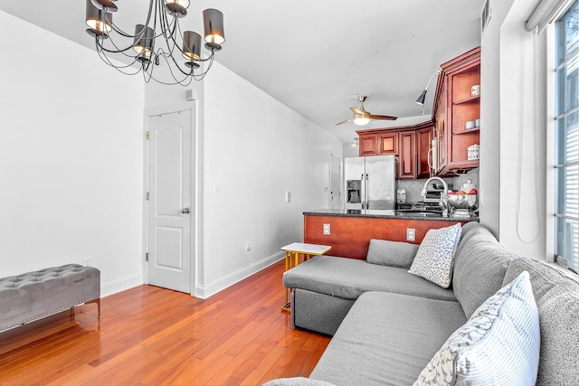 living room featuring visible vents, baseboards, light wood-style floors, and ceiling fan with notable chandelier