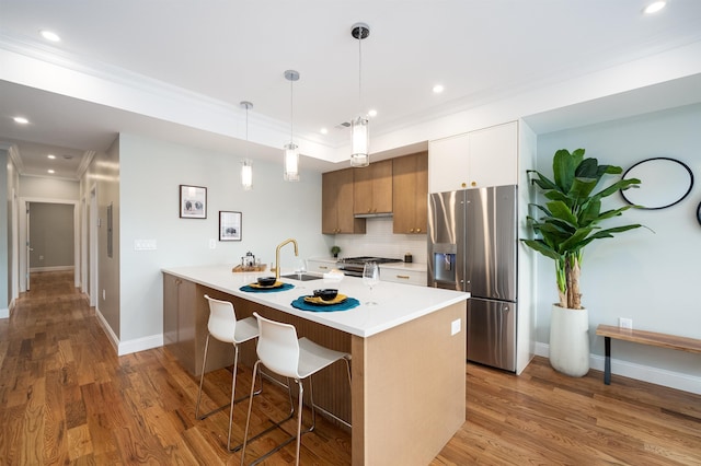 kitchen with stainless steel appliances, tasteful backsplash, light hardwood / wood-style floors, a kitchen bar, and white cabinets