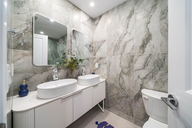 bathroom featuring toilet, vanity, tile patterned floors, and tile walls