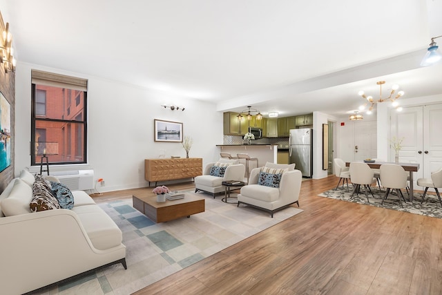 living room featuring a wall mounted air conditioner, a chandelier, and light wood-type flooring