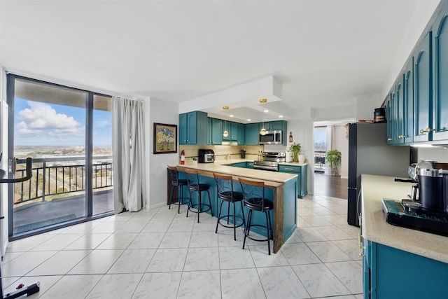 kitchen with a peninsula, a breakfast bar, stainless steel appliances, and light countertops