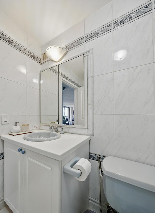 half bath featuring toilet, vanity, and tile walls