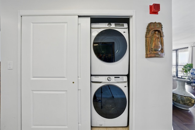 laundry area featuring laundry area, stacked washing maching and dryer, and wood finished floors