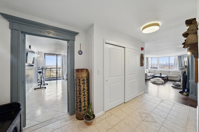 hallway with light tile patterned flooring, a wealth of natural light, and baseboards