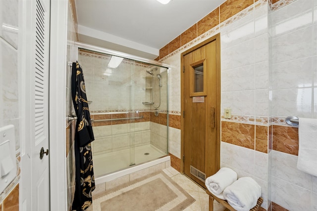 full bath with a stall shower, visible vents, tile walls, and tile patterned floors