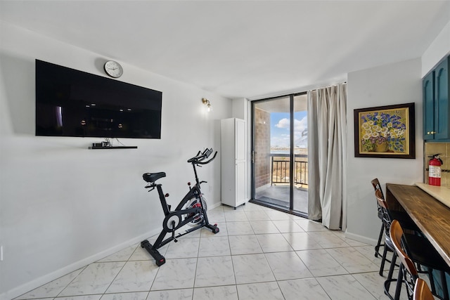 exercise room with marble finish floor, floor to ceiling windows, and baseboards