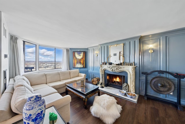 living area featuring a decorative wall, wood finished floors, and a high end fireplace